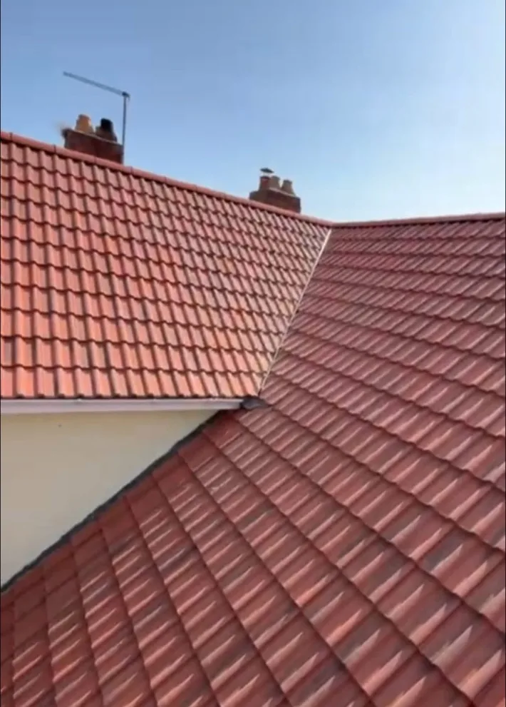 A finished red tiled roof meeting at a valley
