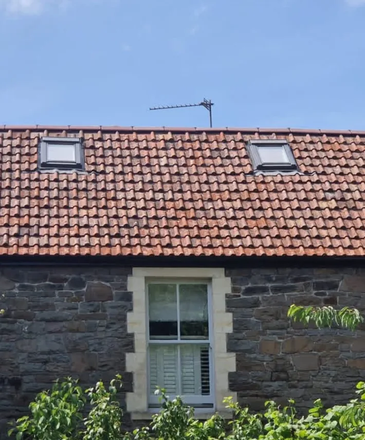 A traditional stone property in Clevedon after a full roof refurbishment, with its original clay tiles reused around two rooflights